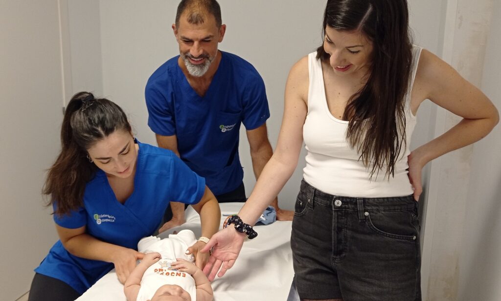 Fisioterapeuta pediátrica explicando a una familia cómo favorecer el tummy time y el desarrollo motor del bebé.